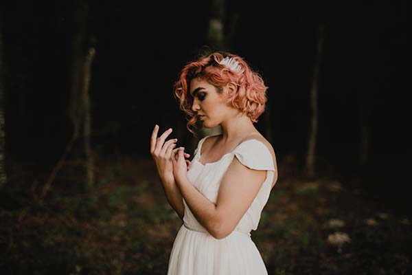 Élégante mariée dans un joli dress blanc, les tons chauds de ses cheveux rose offrent un contraste saisissant contre