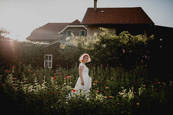 Une jeune femme dans un joli robe blanche se promène dans un jardin fleuri, évoquant l'élégance et la beauté de la nature.