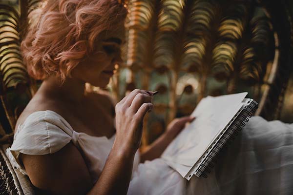 Une jeune femme en robe blanche, peignant dans un décor naturel et romantique.