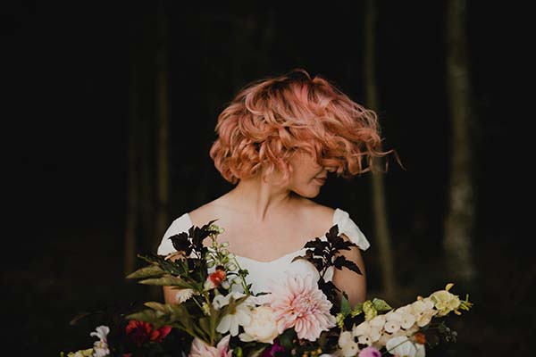 Une mariée dans un décor naturel, tenant un bouquet de fleurs vibrantes et élégantes.