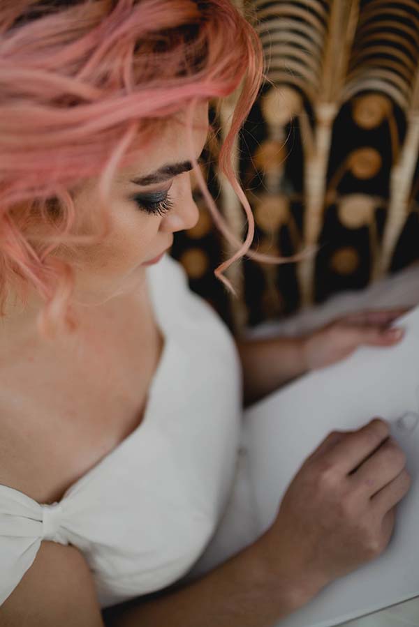 Élégante mariée en robe blanche, plongée dans la création d'un dessin dans un décor inspiré des années 20.
