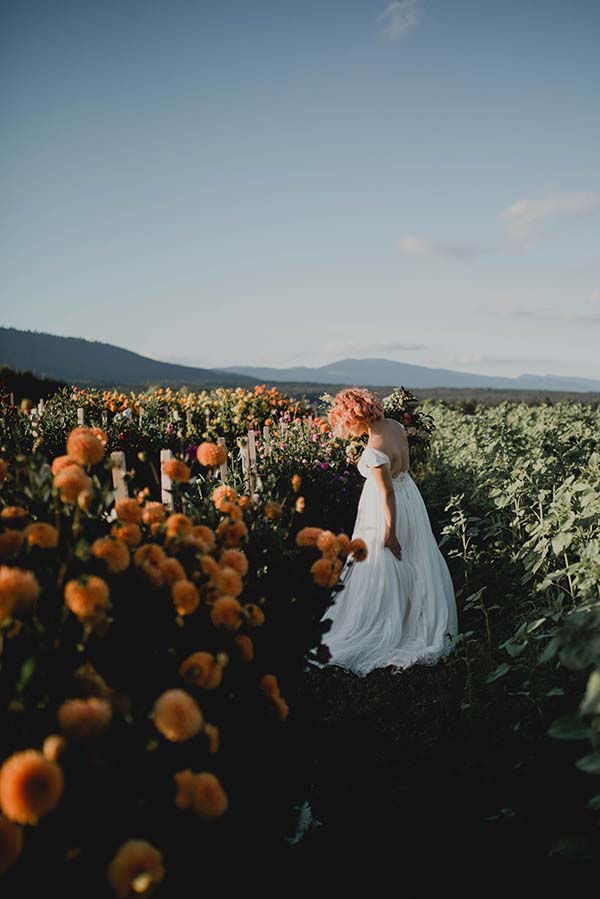 Une mariée dans un beau robe blanc se promène dans un champ de fleurs, créant un ambiance romantique et paisible.