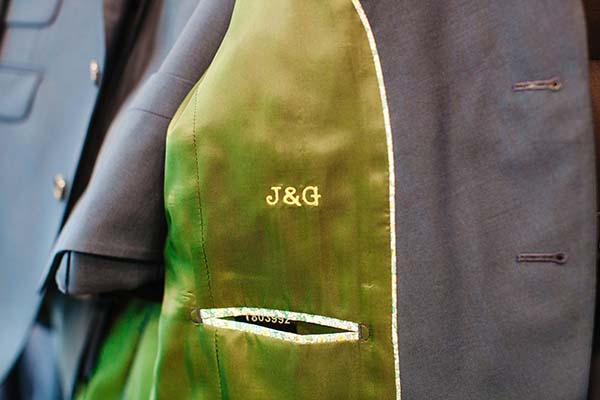 Un costume vert vif avec une étiquette "J&G" et un code de taille visible, prêt à être habillé.