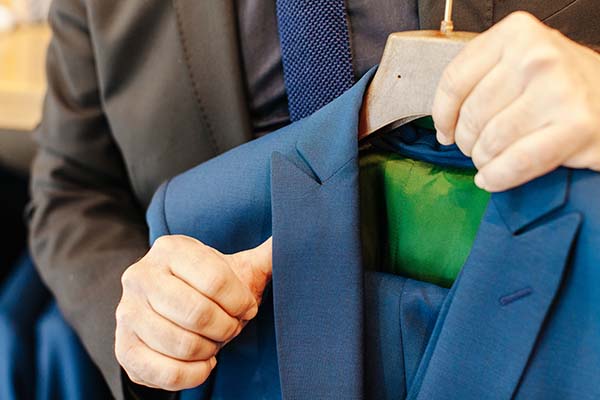 Tailleur à travail en cours, ajustant un costume bleu avec un foulard vert caché.