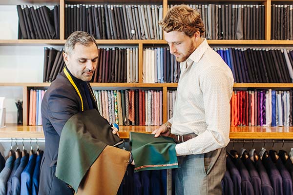 Un homme habile examine un tissu vert pour un client dans un magasin de vêtements de formalité élégant.