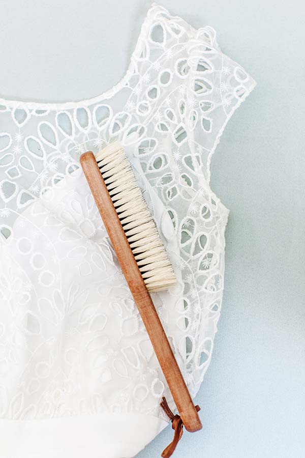 Robe blanche élégante avec dentelle, accompagnée d'un brosse en bois, idéal pour entretenir votre robe de mariée.