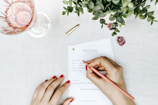Un instant romantique et intime, avec un pinceau rose dans une main ornée de manicure rouge, signe de préparation pour un mariage.