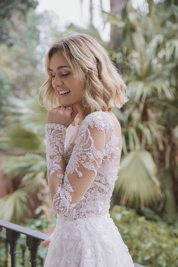 Une jeune femme charmante dans un magnifique robe de mariage blanc avec des motifs floraux délicats, souriant doucement