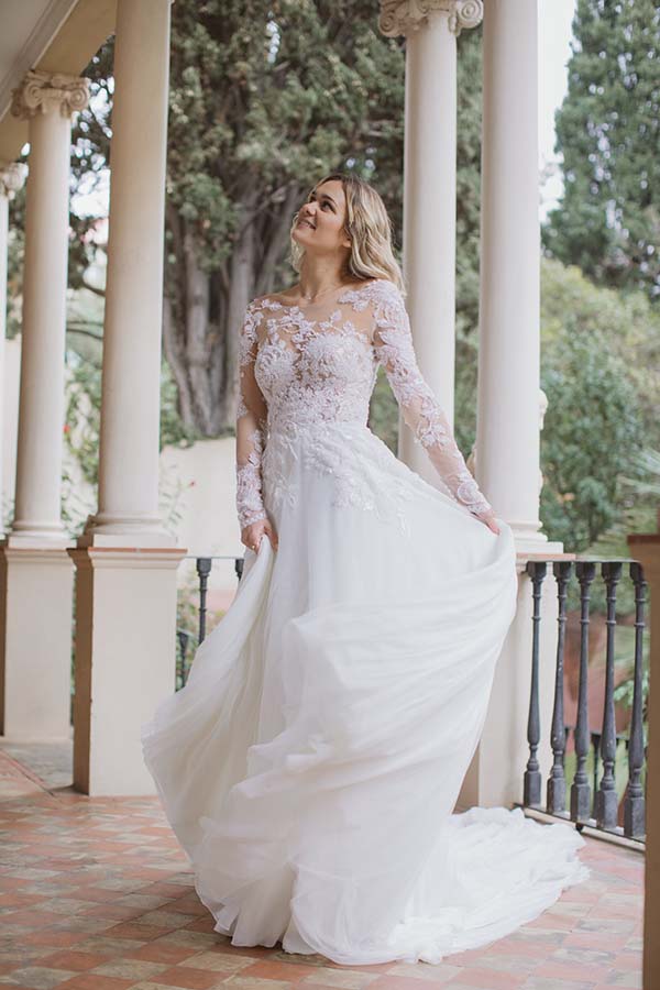 Magnifique robe de mariage blanche avec des détails délicats et des manches longues, dans un décor charmant et romantique.