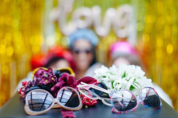 Un photobooth coloré avec des lunettes de soleil et des fleurs, idéal pour un mariage joyeux et vibrante.