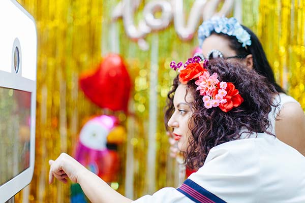 Un couple amoureux dans un photobooth coloré et joyeux, décoré de fleurs et de ballons, pour capturer des moments
