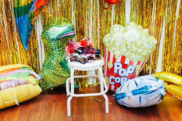 Un photobooth coloré et ludique avec des ballons, une chaise et des décorations pour un mariage joyeux et unique.