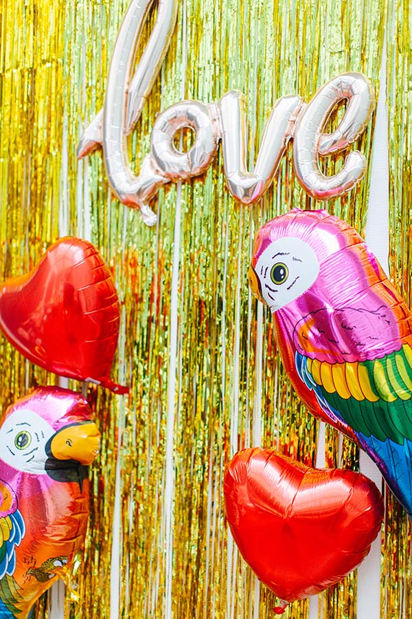 Photobooth vibrants avec ballons en forme de cœur et d'oiseau, décoré de soie dorée, idéal pour un mariage coloré et joyeux.