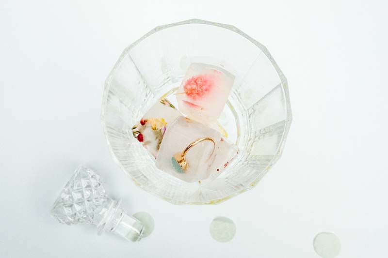 Jardin de rêve avec une bague de mariage et des délicates fleurs de savon dans un verre crystal.