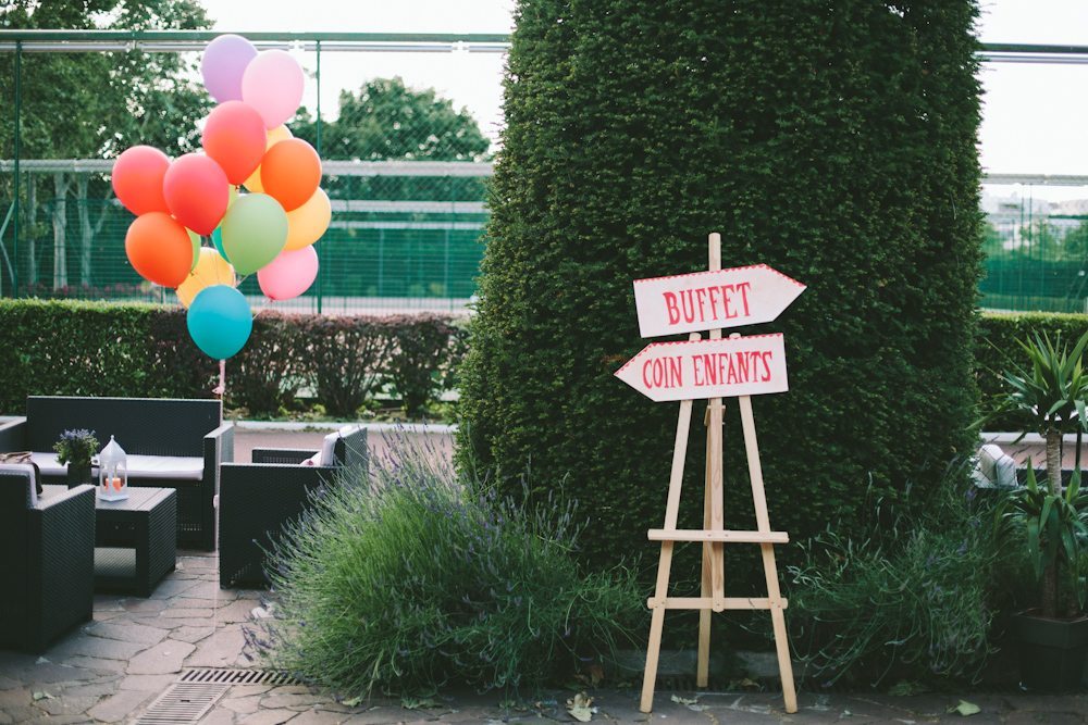 Un décor charmant pour un mariage de famille avec un panneau indiquant l'accès au buffet et un coin pour les enfants,