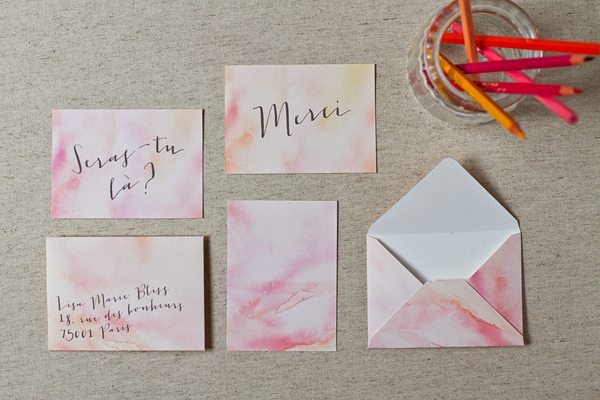 Papeterie de mariage faite main avec des touches d'aquarelle rose et orange et une calligraphie élégante.