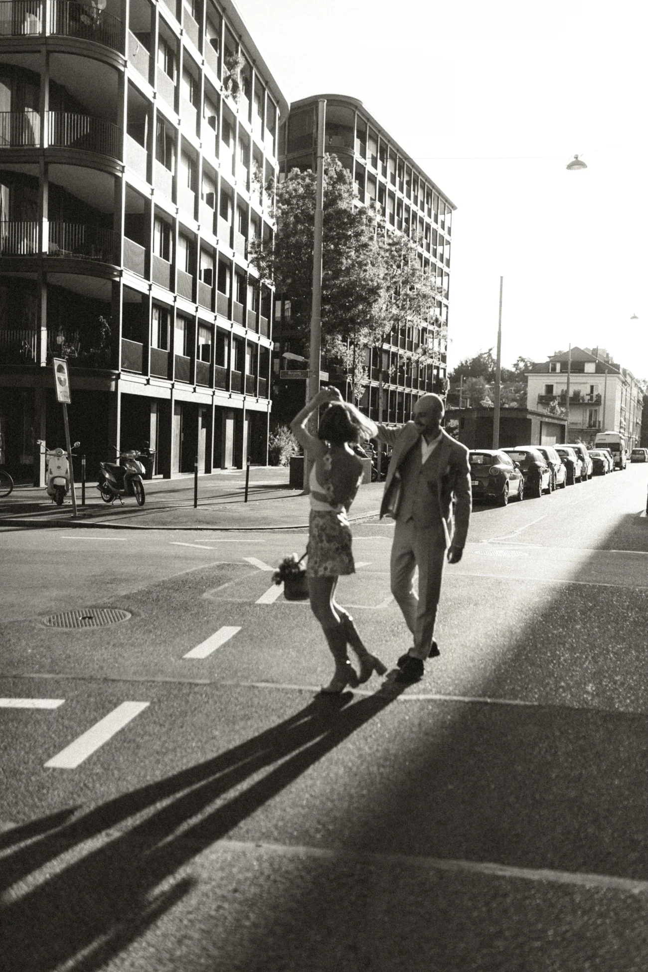 Couple élégant dansant sur un passage piéton en ville, photographie noir et blanc à l'ambiance rétro et romantique.
