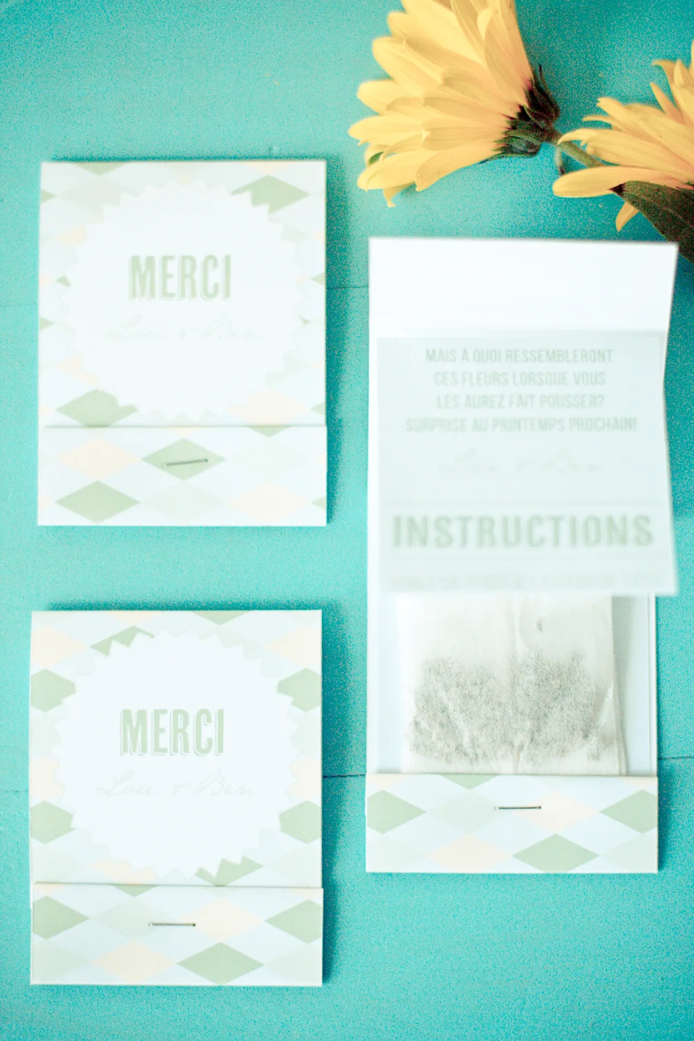 Cartes de remerciement et sachets de graines pastel sur fond turquoise, accompagnés de fleurs jaunes.