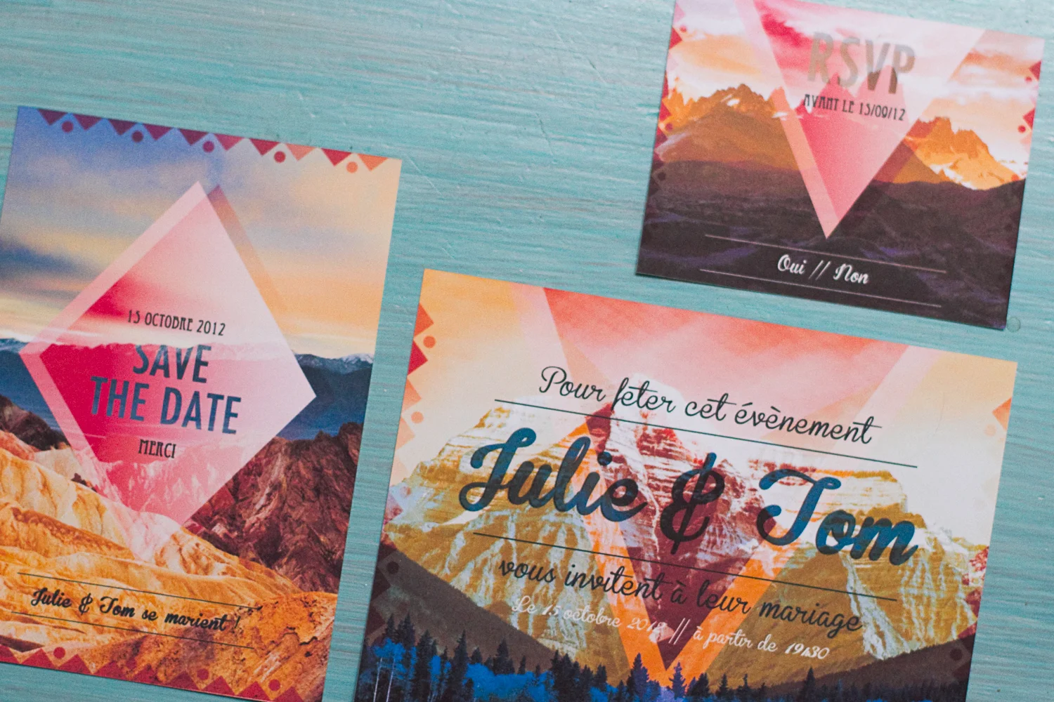 Faire-part de mariage colorés aux motifs géométriques et paysages de montagne sur un fond bleu turquoise.