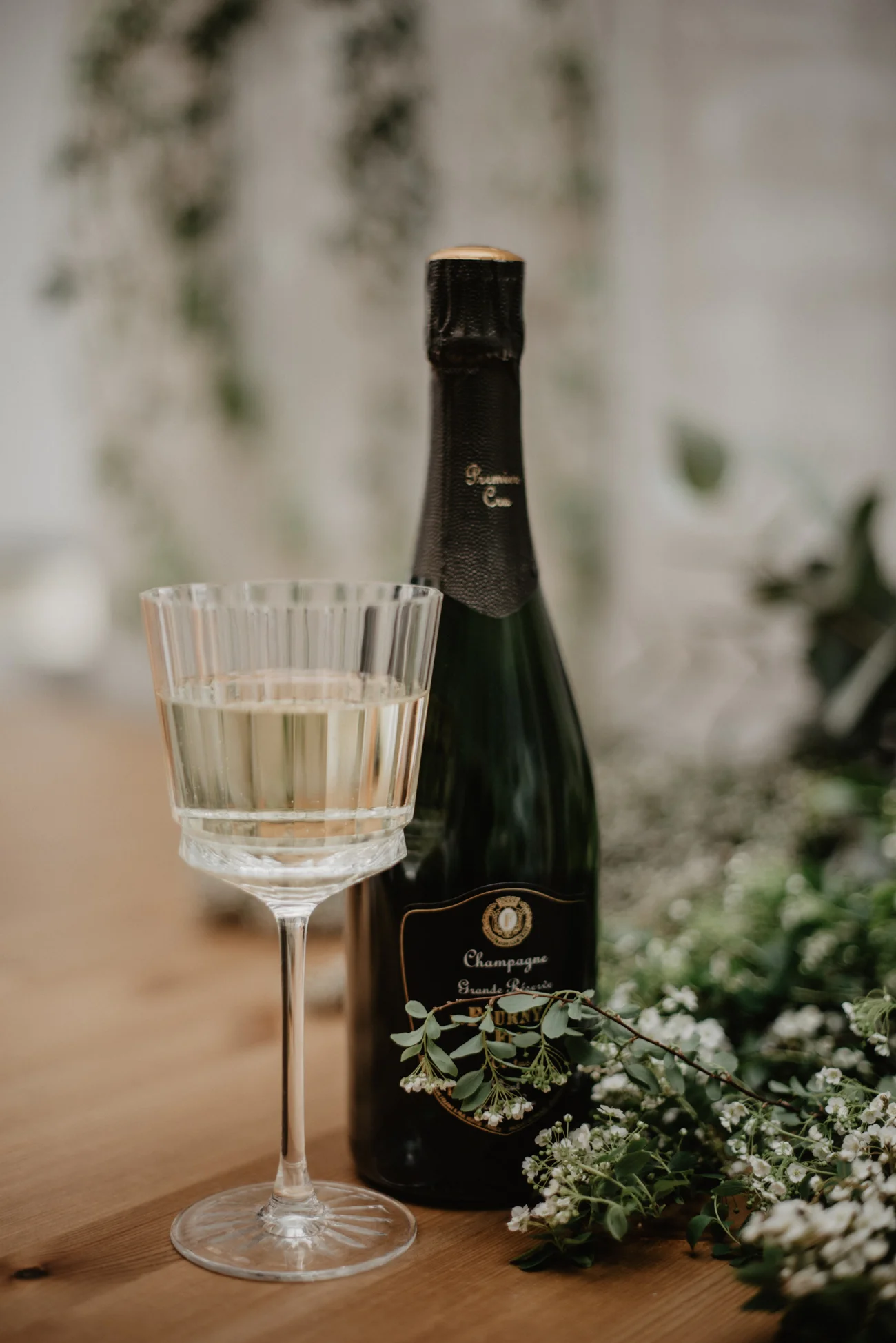 Un verre de champagne frais et un flacon de Champagne Grande Réserve, décoré de fleurs blanches, suggèrent un choix de