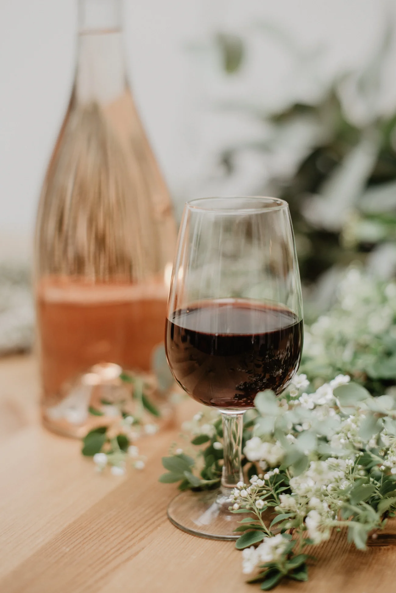 Un verre de vin rouge riche et un verre de vin rose élégant entourés de fleurs blanches fraîches, idéal pour un mariage.