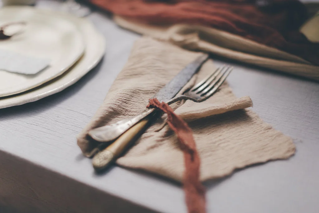 Évocation poétique d'un repas intime, avec fourchettes et couteau soigneusement rangés sur un serviette raffinée,