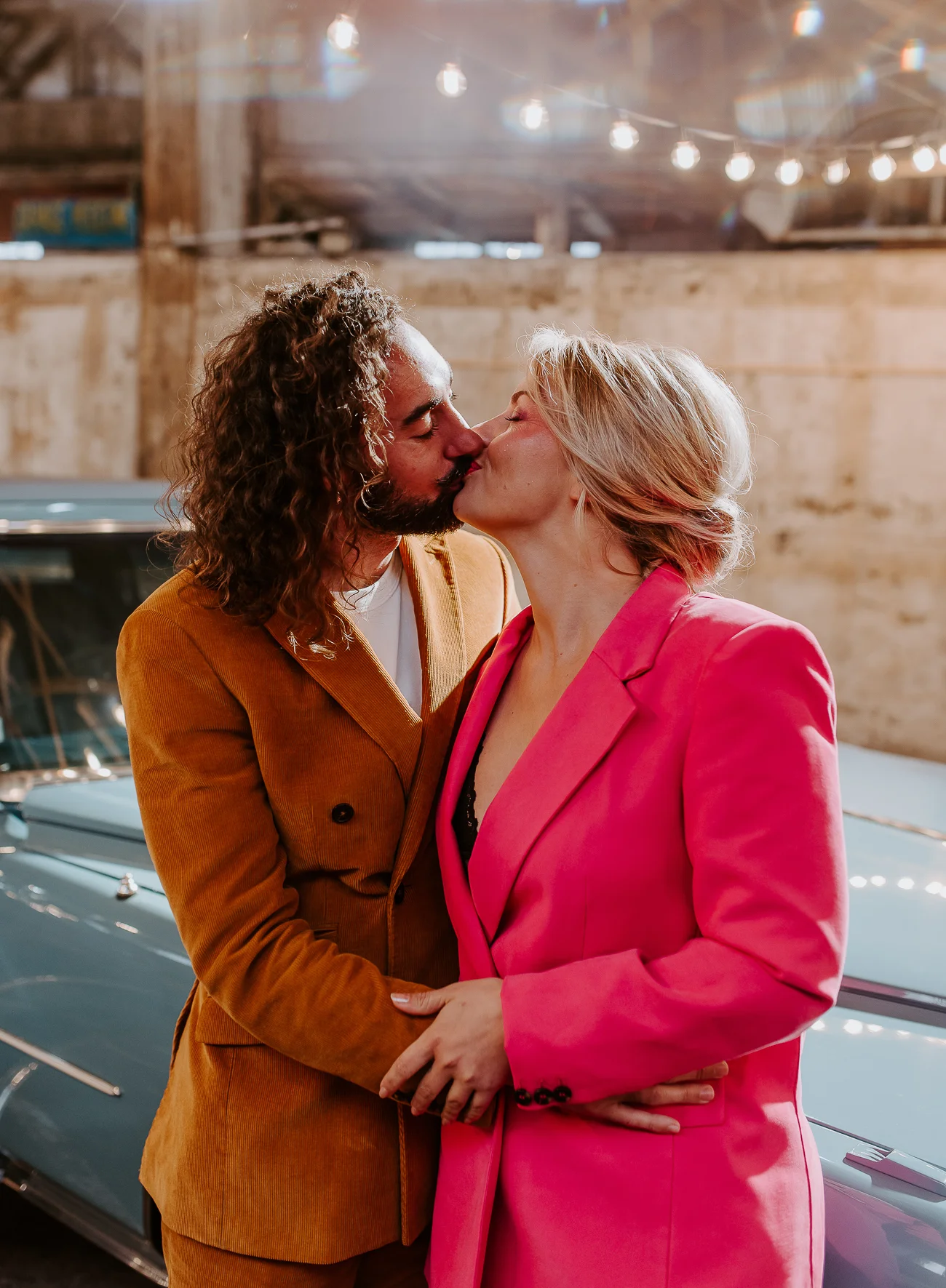 Un couple romantique partage un baiser tendre devant un vintage bleu, incarnant l'ambiance unique d'un mariage Pink Bowie.