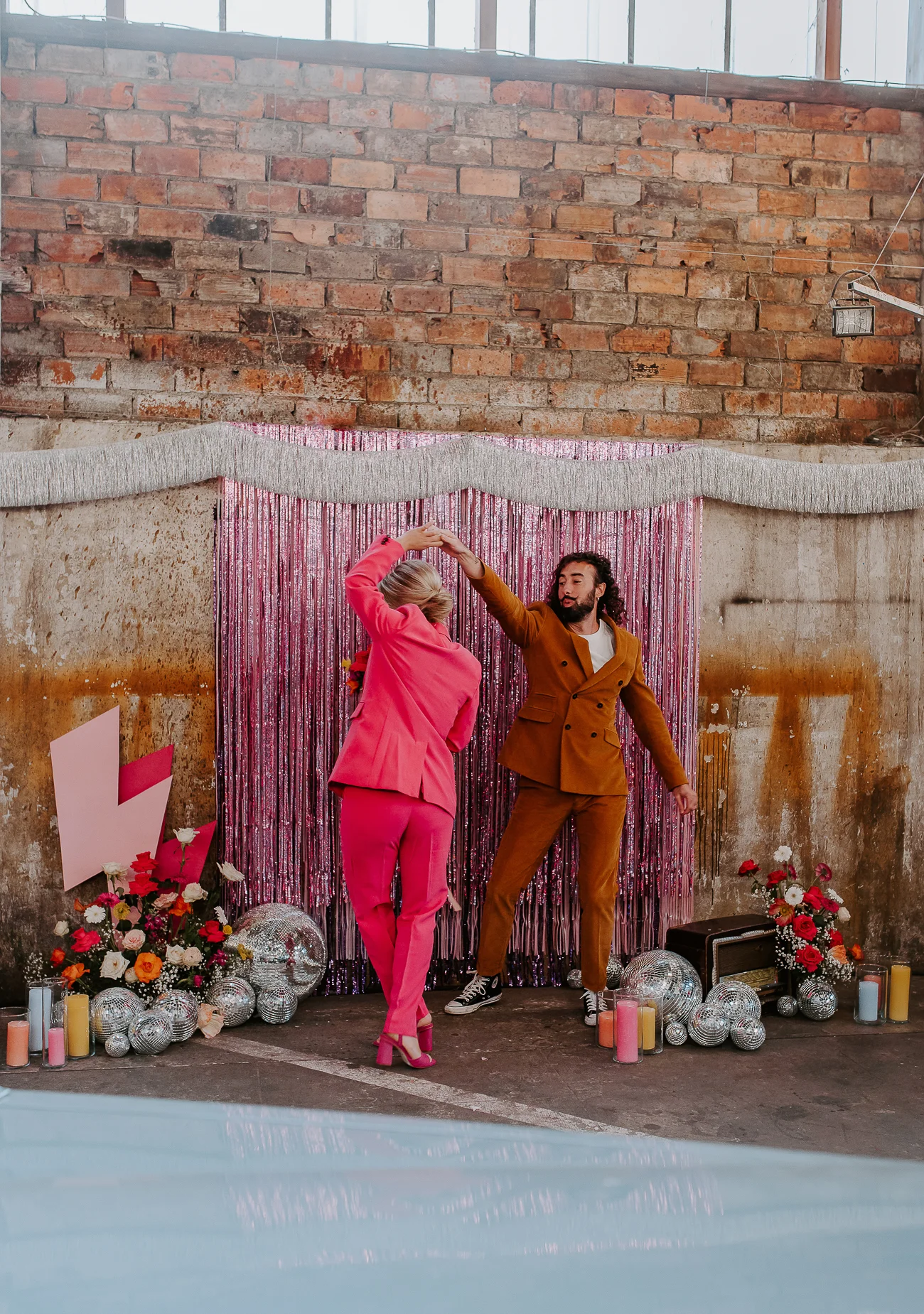 Un couple dans des costumes vifs dans un décor coloré et fantaisiste pour un mariage inspiré de Bowie.