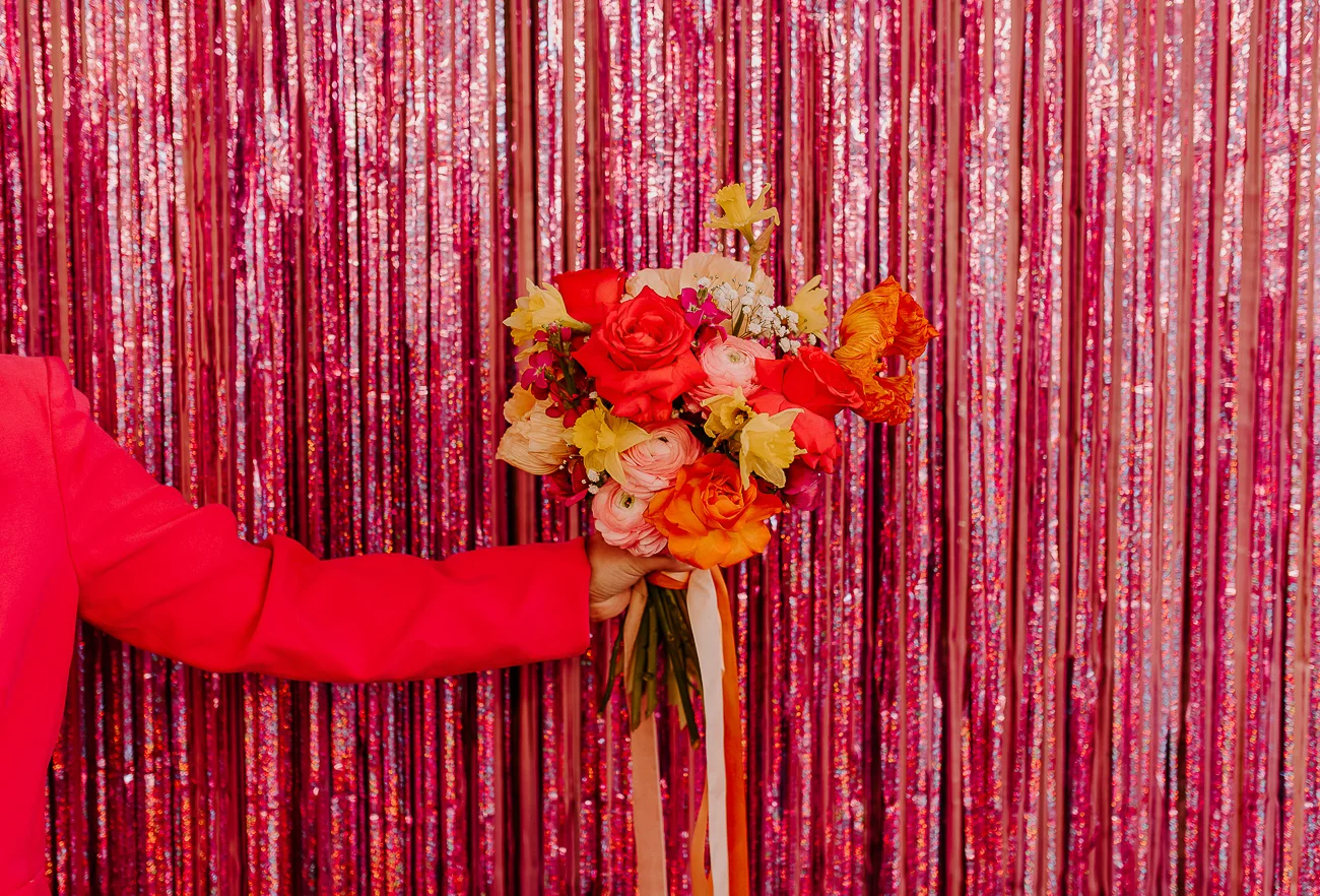 Un bouquet vibrante de fleurs roses et orange contre un fond de rideaux en perles rouges, créant un atmosphère