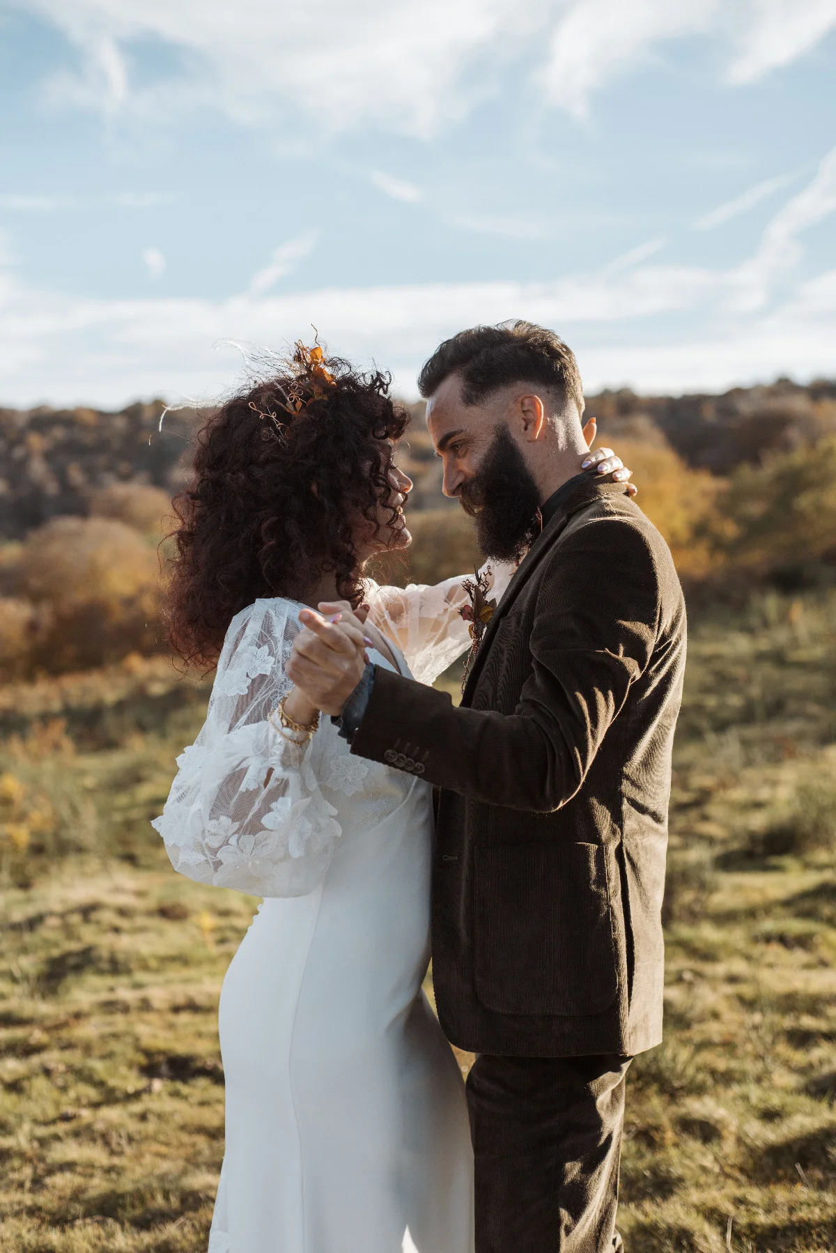 Couple en tenue folk dansant tendrement en pleine nature sous un ciel clair.