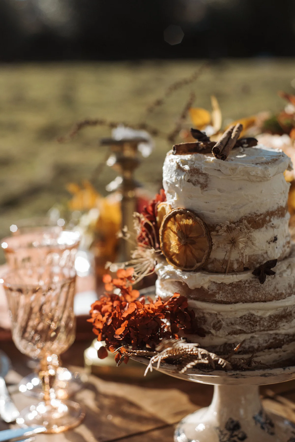 Gâteau de mariage naked cake décoré de tranches d'orange et fleurs séchées dans une ambiance folk et naturelle.