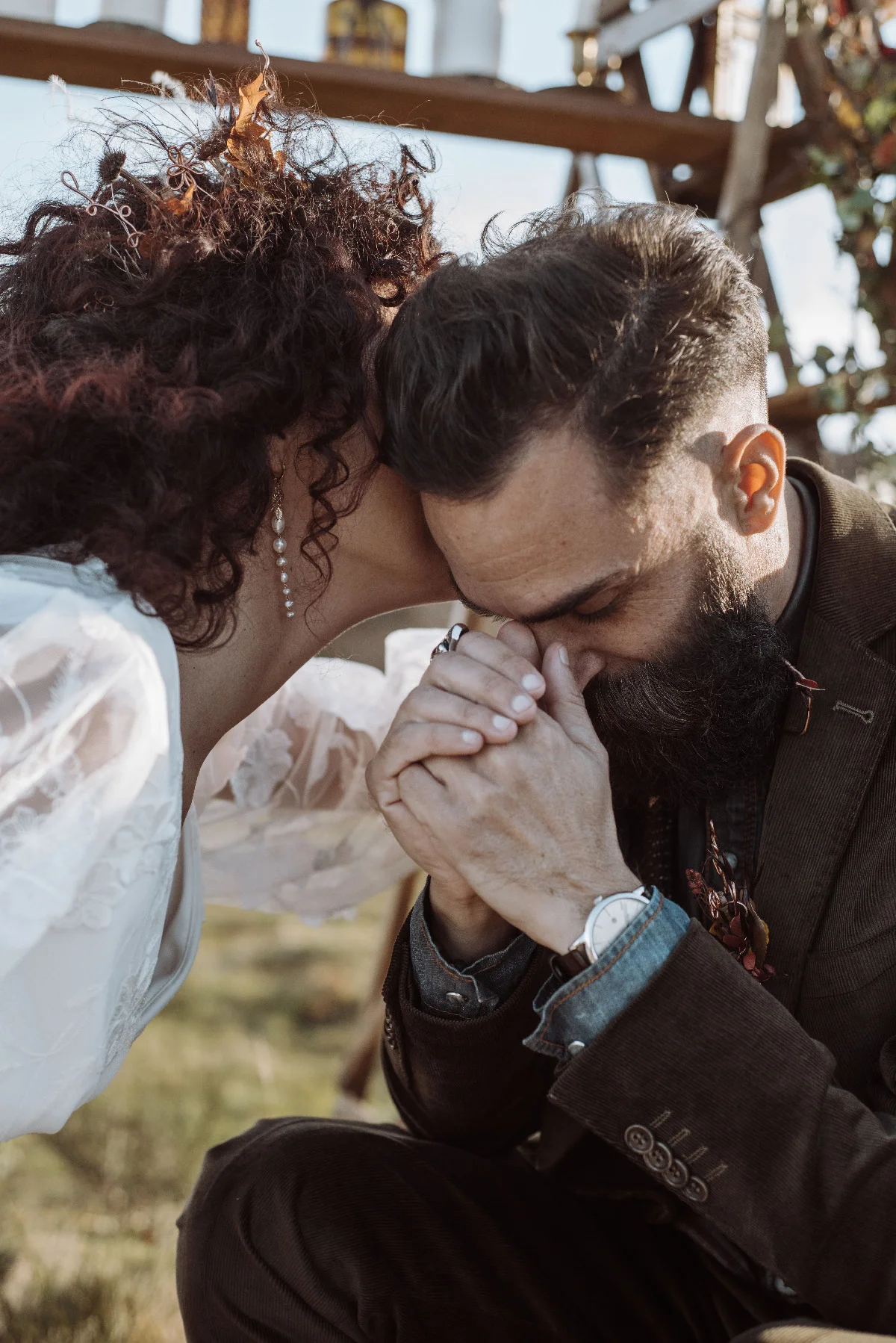 Couple en tenue folk s'embrassant tendrement dans un cadre naturel et chaleureux.