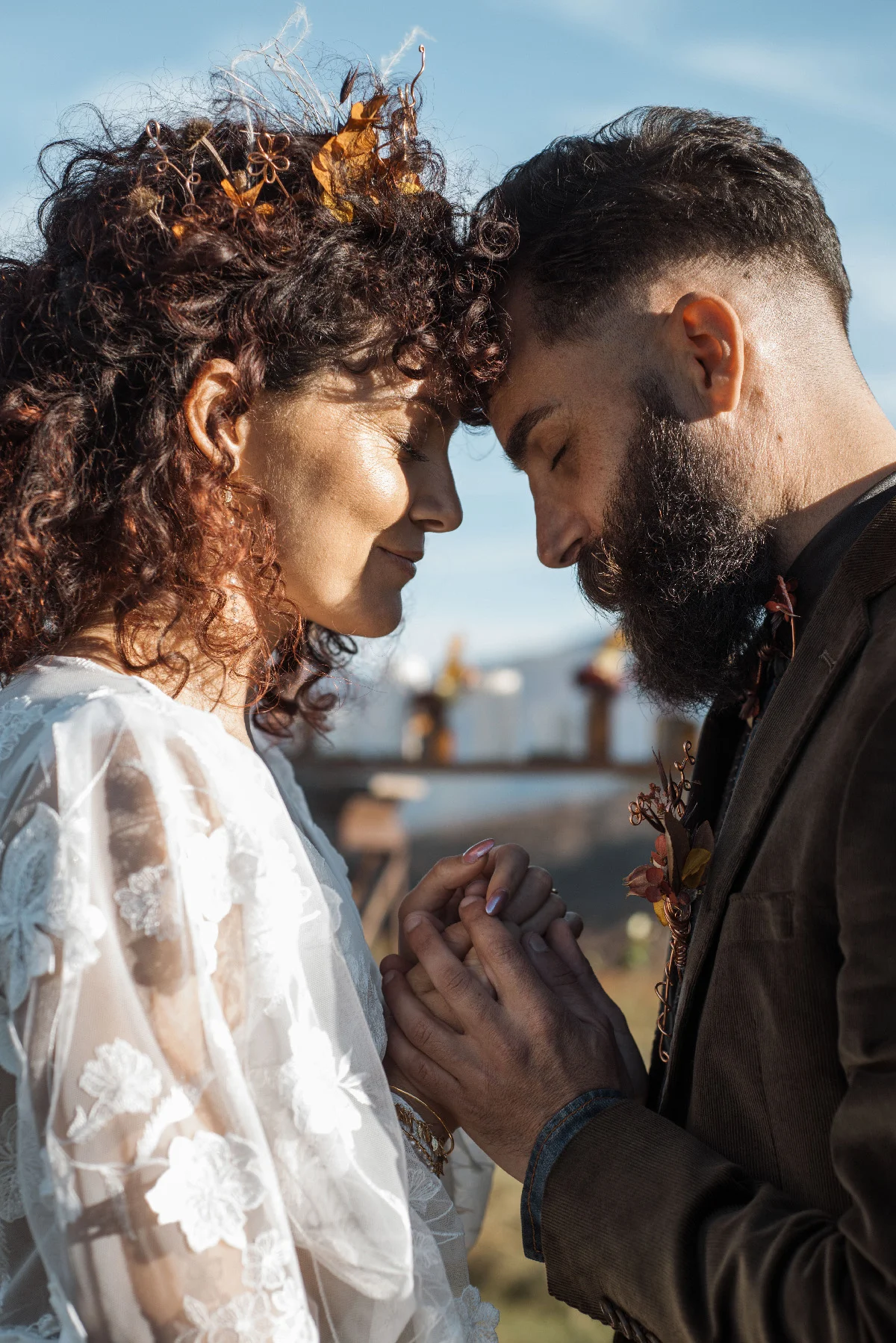 Couple en tenue folk, front contre front, s'tenant la main dans une ambiance romantique et naturelle.
