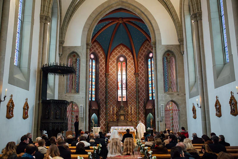 Mariage de Victoire et Xavier dans une église gothique aux vitraux colorés et à l'architecture solennelle.