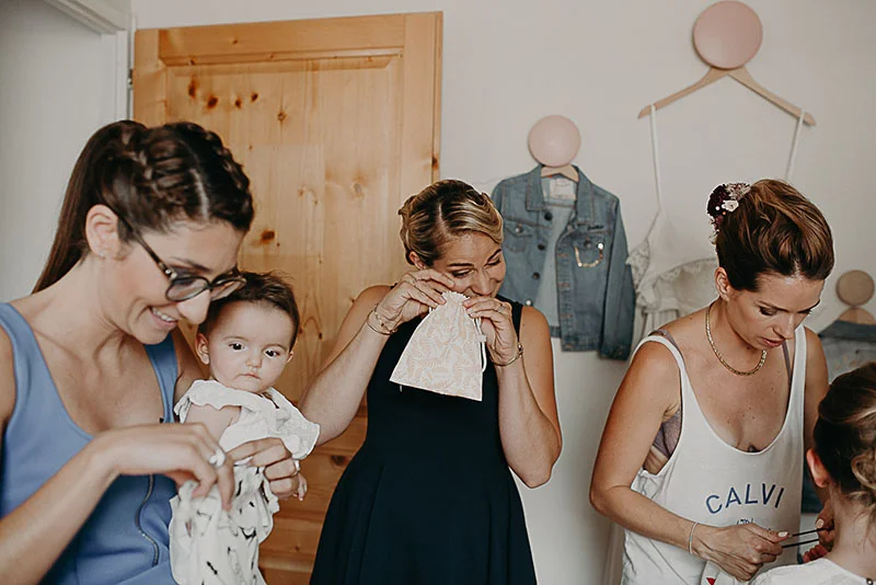Trois femmes et un bébé partagent un moment complice et émouvant lors des préparatifs du mariage.