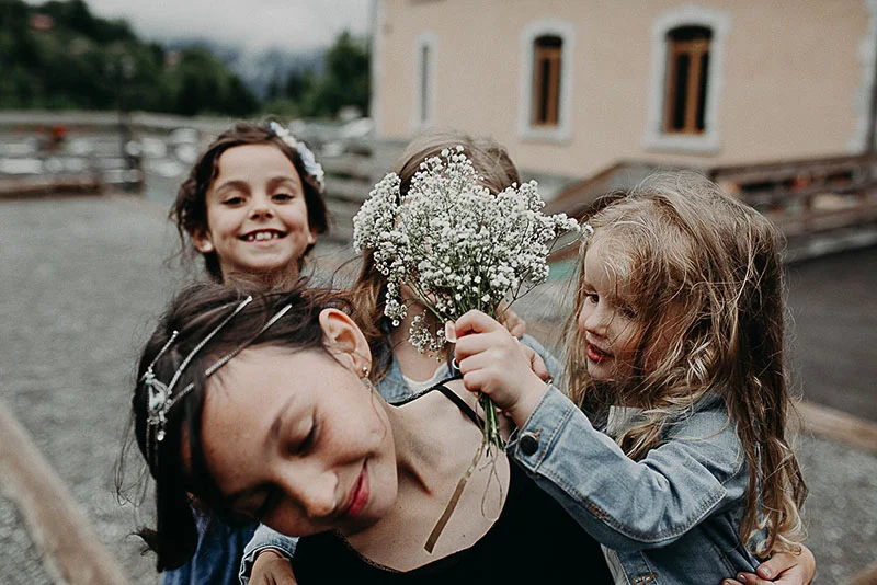 Une femme et trois petites filles rient ensemble, l'une d'elles tenant un bouquet de gypsophile blanc.