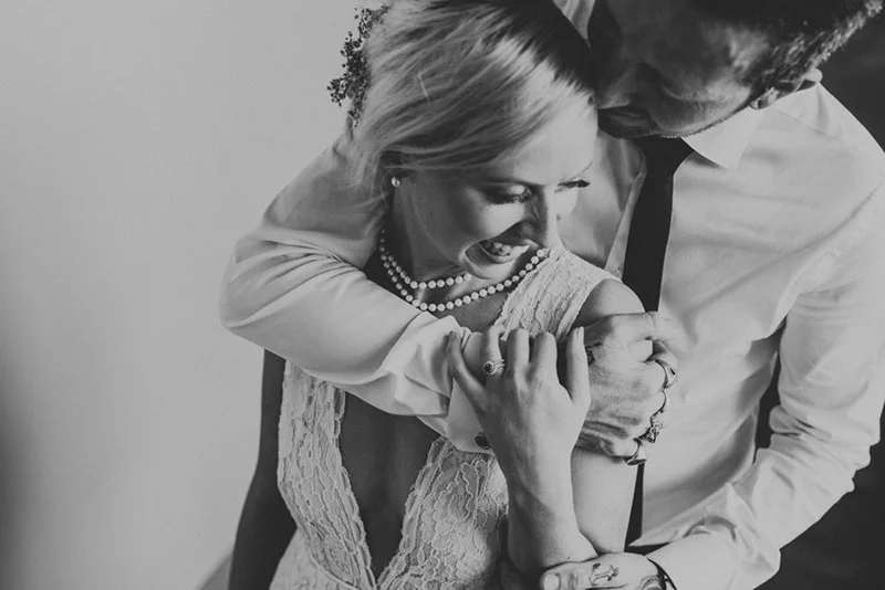 Couple de mariés riant ensemble dans une étreinte tendre, photographie en noir et blanc.