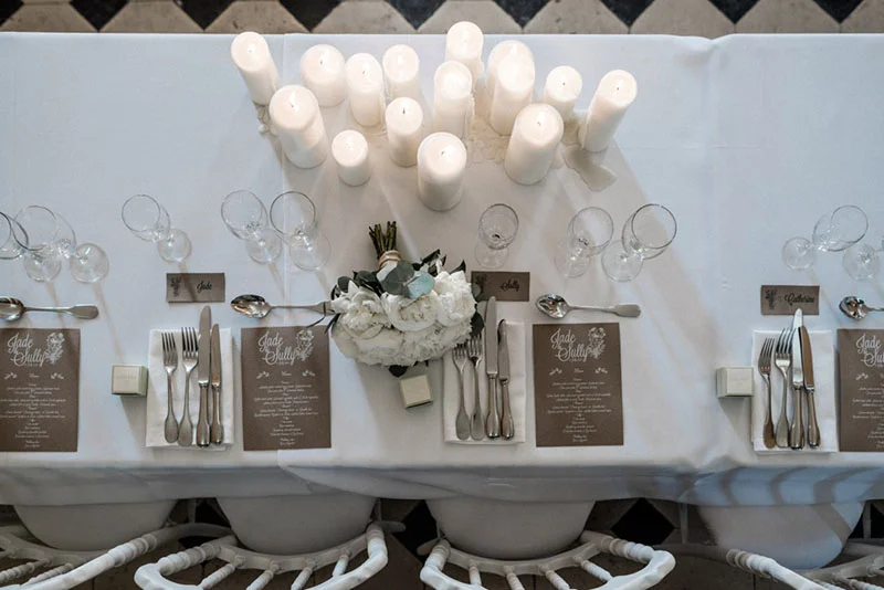 Table de mariage élégante et blanche avec bougies, fleurs blanches et menus personnalisés pour Jade et Sully.