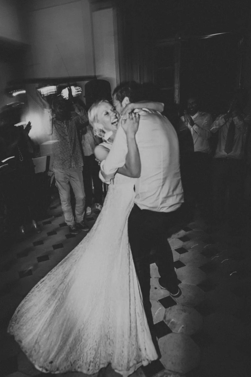 Couple de mariés s'enlaçant joyeusement lors d'une soirée festive, photographie en noir et blanc.
