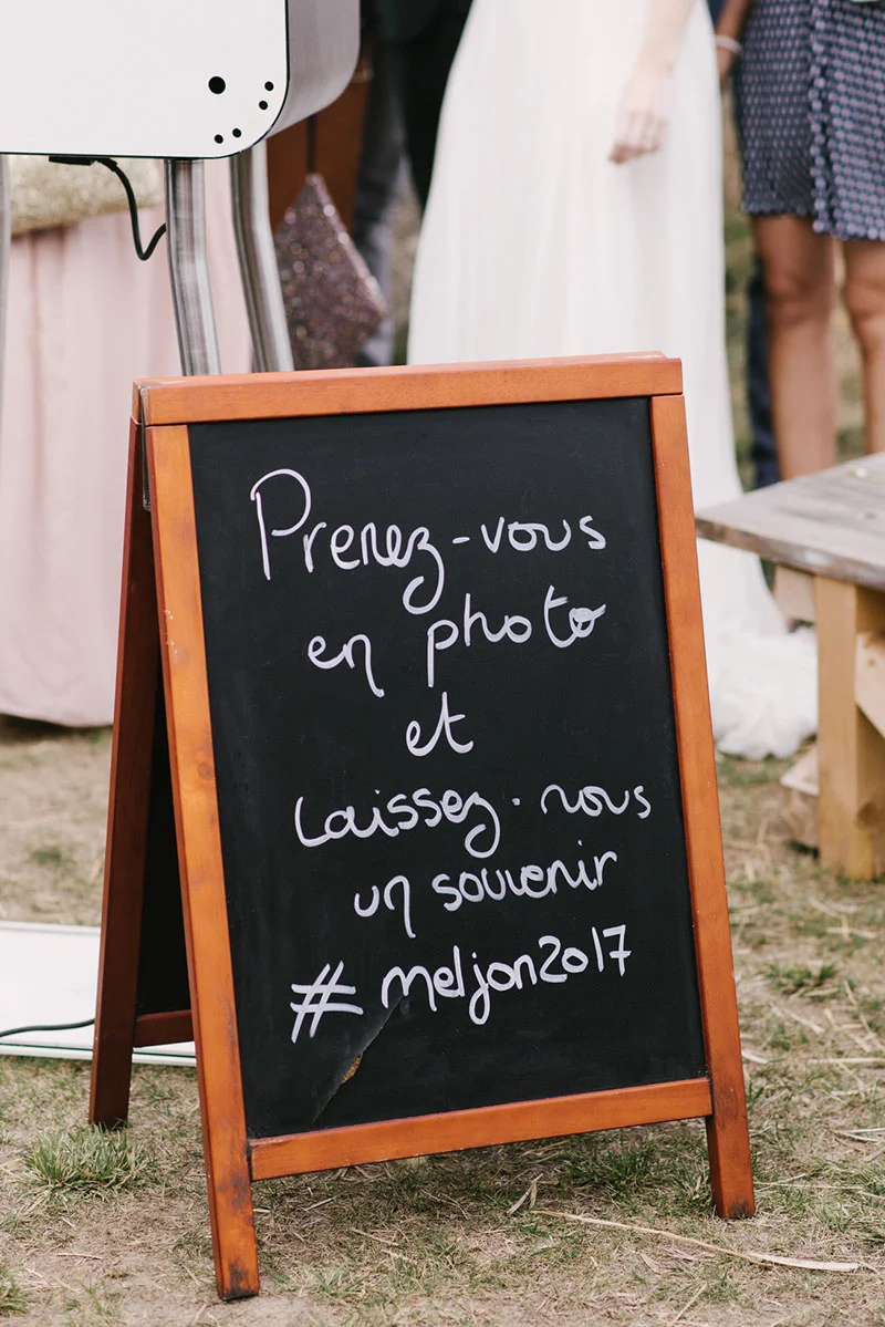 Ardoise en bois invitant les invités à se photographier avec le hashtag #meljon2017 lors d'un mariage en extérieur.