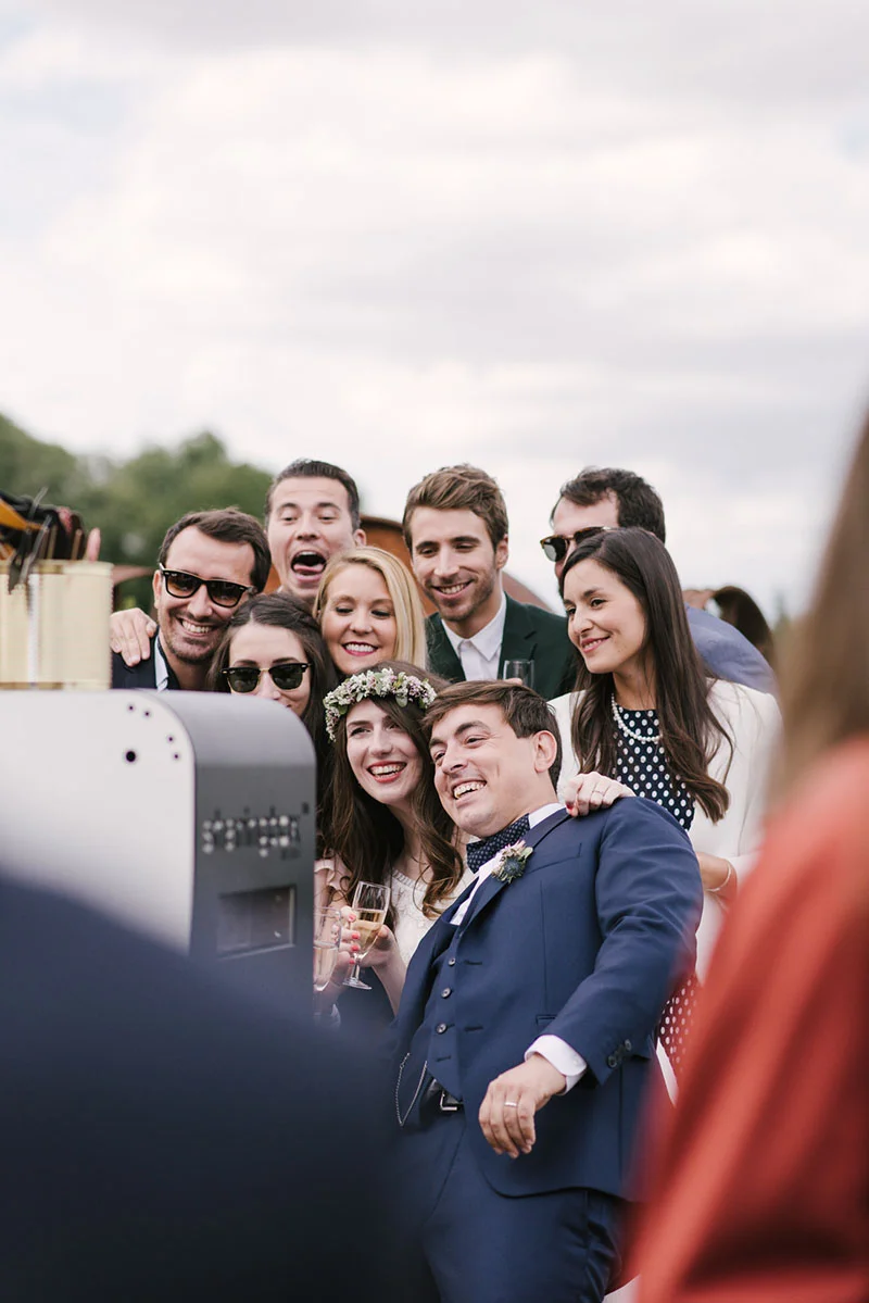 Un groupe d'invités souriants et élégants pose pour un photobooth lors du mariage de Mélanie et Jonathan.