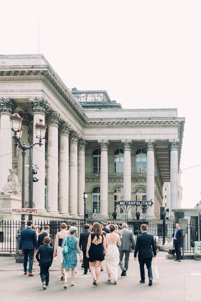 Couple de mariés et leurs invités marchant devant un bâtiment classique avec l'inscription Métropolitain.