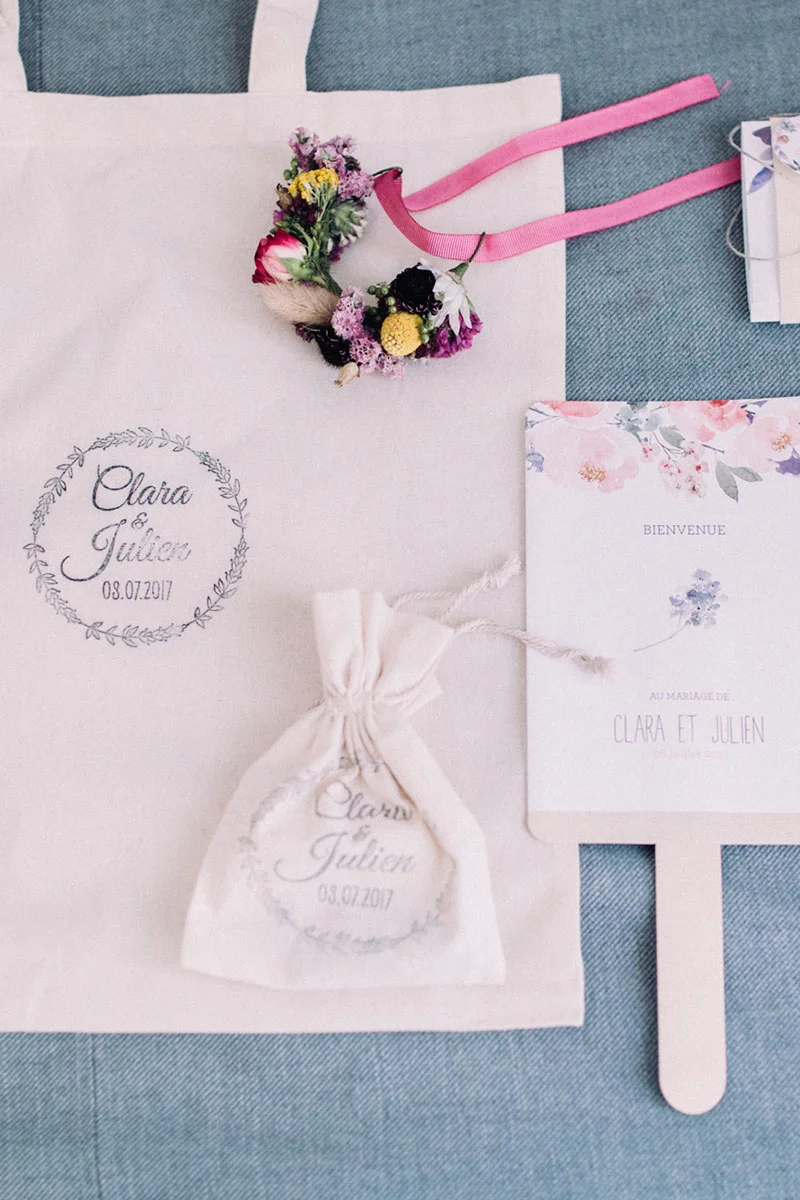 Accessoires de mariage personnalisés pour Clara et Julien : tote bag, pochon, couronne de fleurs et carte de bienvenue.