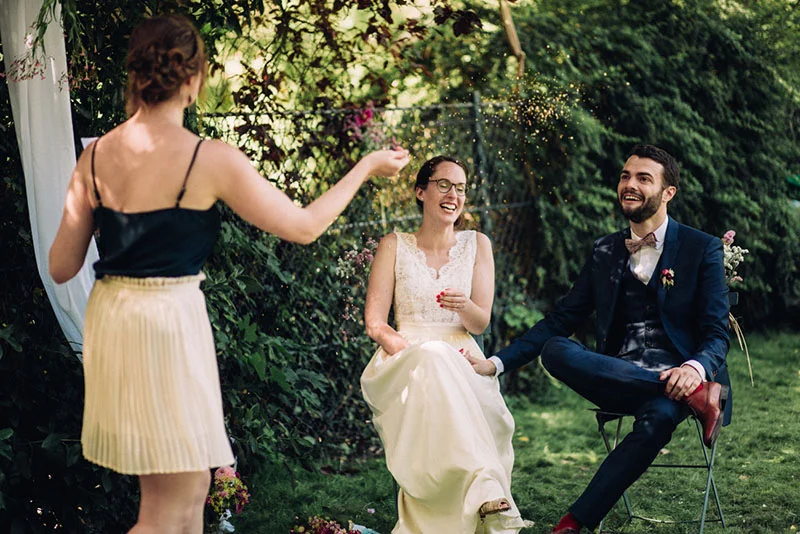Une mariée et son époux rient sous une pluie de confettis dorés lors d'une célébration joyeuse en plein air.