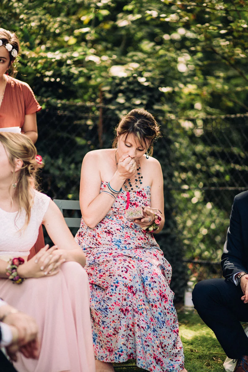 Une invitée en robe fleurie colorée essuie une larme avec émotion lors du mariage de Clara et Julien.