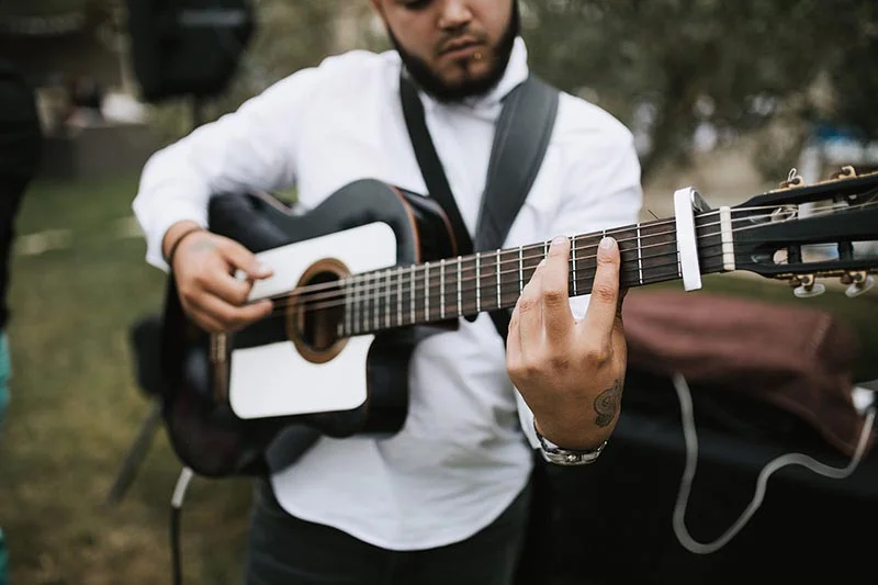 Musicien en chemise blanche jouant de la guitare acoustique lors du mariage de Pauline et Florent.