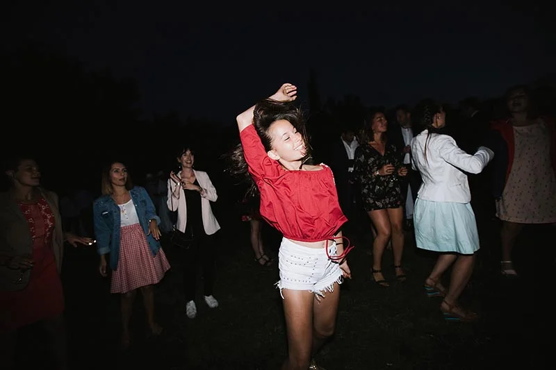 Une jeune femme en haut rouge et short blanc danse avec joie lors d'une soirée festive nocturne.