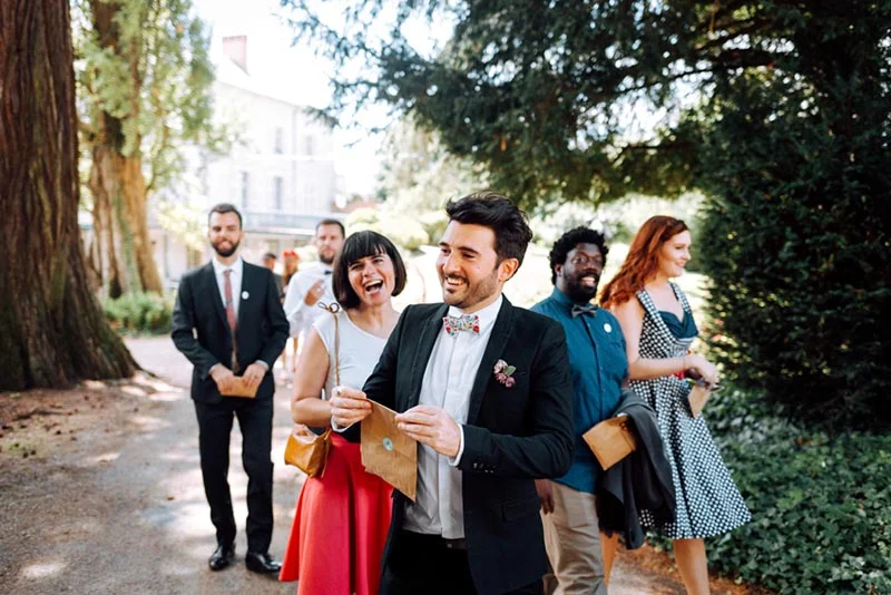 Invités souriants et élégants marchant en extérieur lors du mariage de Mel et Ben.