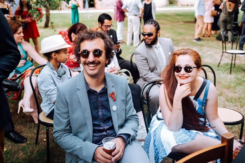 Invités souriants et élégants discutant en extérieur lors du mariage de Mel et Ben.