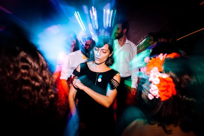 Invités dansant lors de la soirée de Mel & Ben, capturés avec un effet de flou artistique et des lumières colorées.